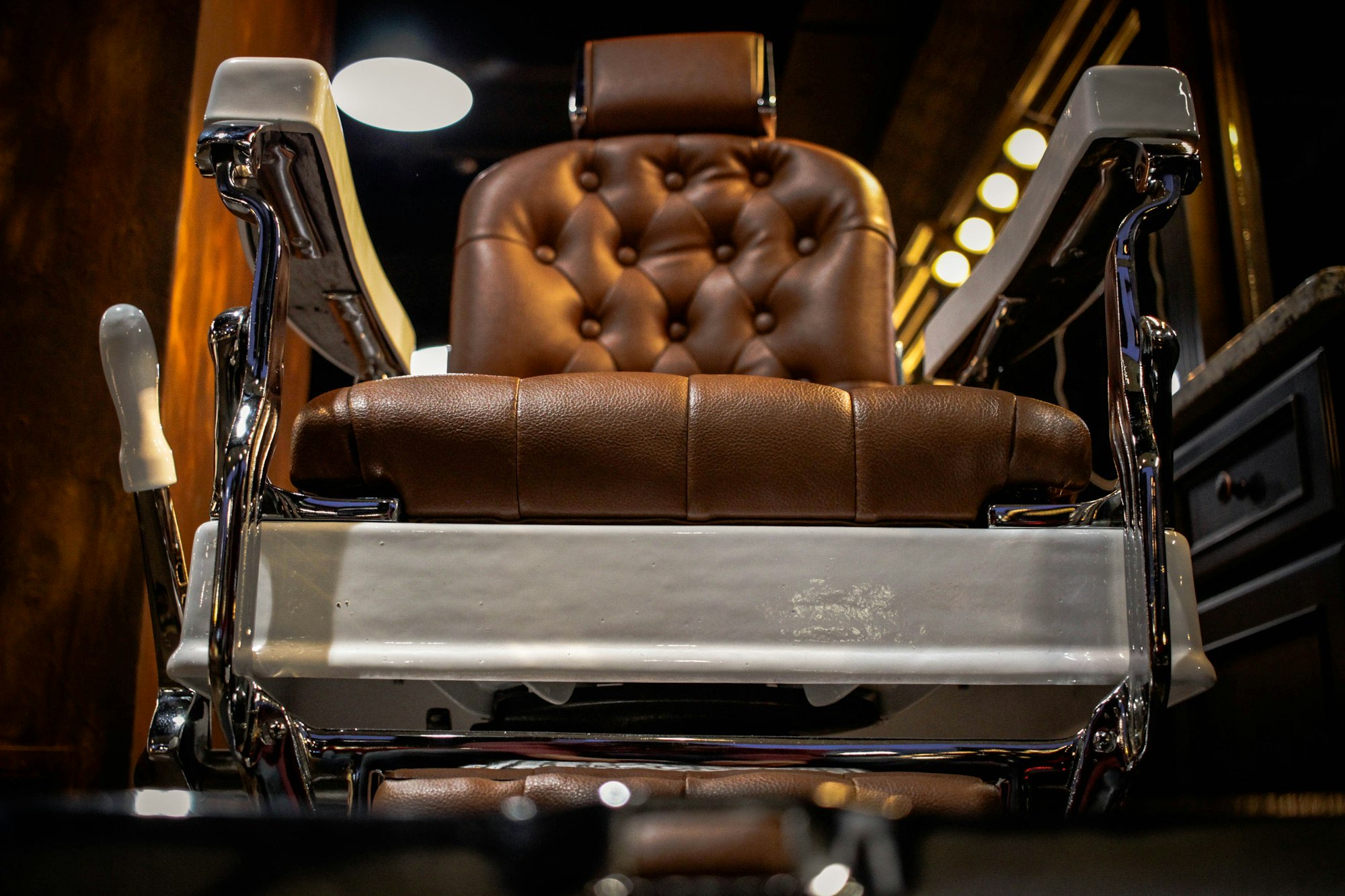 Warm tufted leather barber chair with chrome details in ambient light