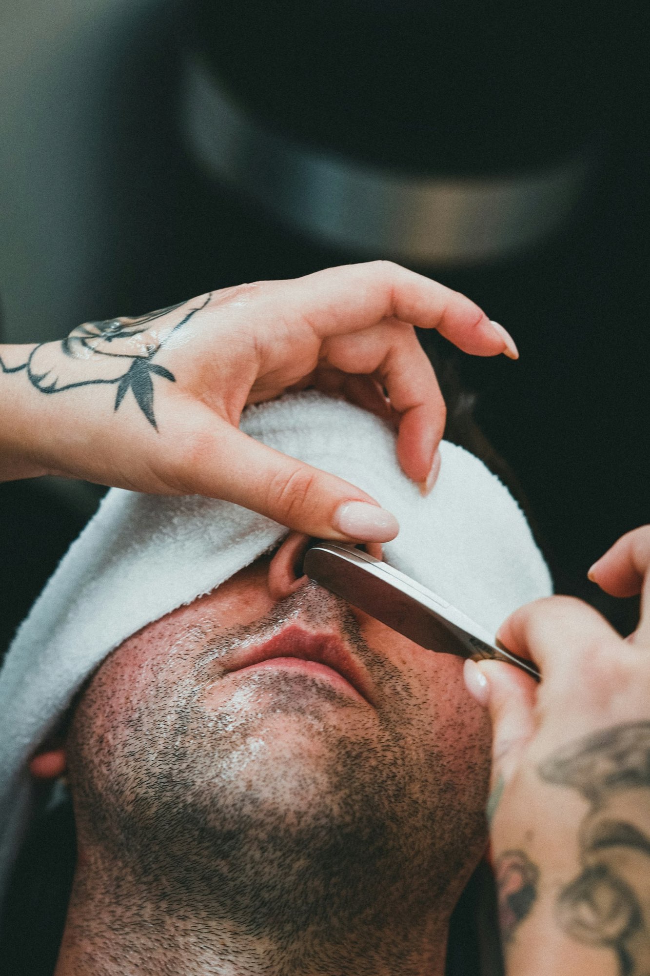 A hot towel covers a client's eyes during a straight-razor service